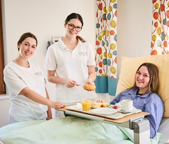 Schüler*innen bringen einer Schülerin Essen ans Pflegebett