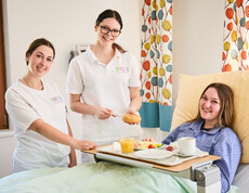 Schüler*innen bringen einer Schülerin Essen ans Pflegebett