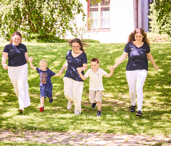Schüler*innen laufen mit Kindern über die Wiese